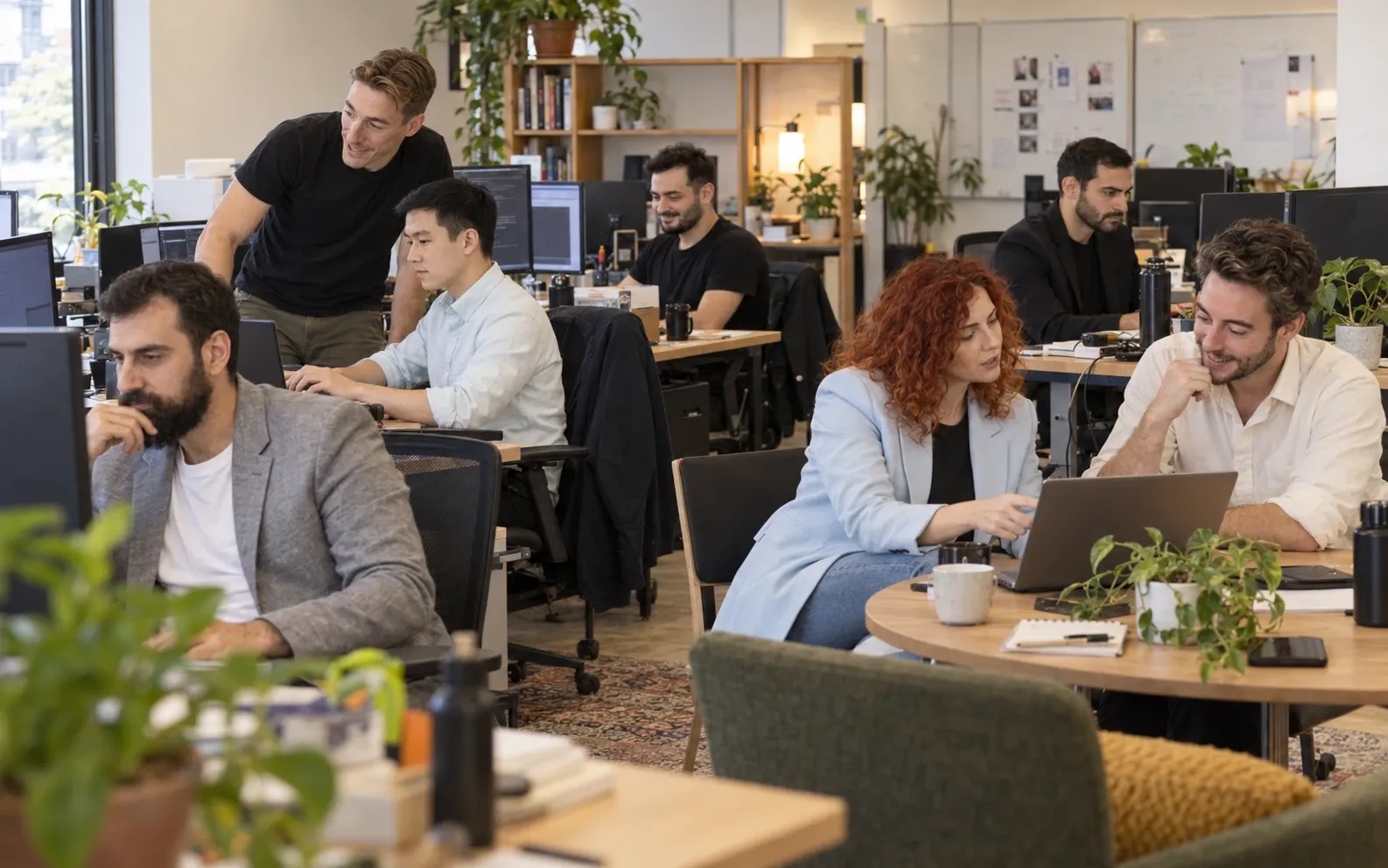 Colleagues working together at desks in a bright office full of plants.